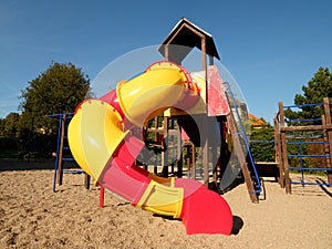 Playground colorful tube slide in public park. New slider tube and wooden ladders