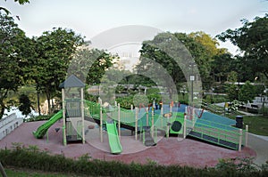 A playground at a garden park with slides, climbers stairs and playhouse