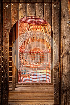 On the playground - inside a rustic wooden climbing tower looking out at orange rope tunnel to climb