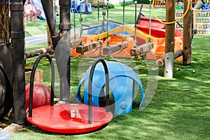 Playground in the park with blue and red seats and swings.