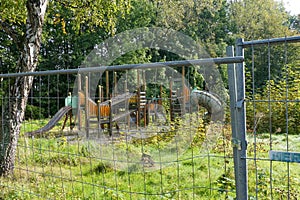 Playground surrounded by plants cordoned off with a fence