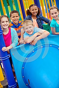 The playground is their favourite hangout. A multi-ethnic group of happy children playing on a jungle gym in a play park