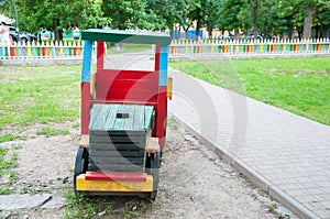 On the playground, a wooden multi-colored train. Near the alley, growing green grass
