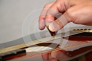 Playing acoustic guitar: hand with pick on strings photo