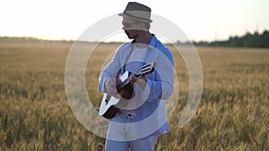 Playing acoustic guitar outdoors in wheat fields