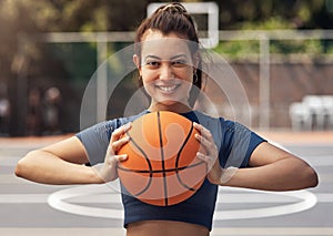 Playing basketball can boost your confidence. Portrait of a sporty young woman holding a basketball on a sports court.