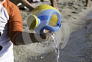 playing on the beach at the sunset time. baby playing with water on sea shore. closeup of the hand holding the watering