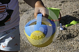 playing on the beach at the sunset time. baby playing with water on sea shore. closeup of the hand holding the watering