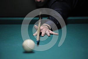 Playing billiard. Player arm gets ready to stroke a ball with a cue