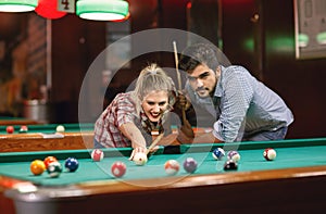 Playing billiards- couple shooting pool ball