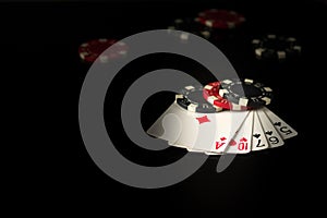 Playing cards on a black table with a high card poker winning combination and chips in the background