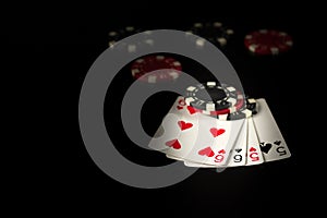Playing cards on a black table with a two pairs poker winning combination and chips in the background