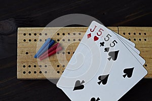 Playing cards and cribbage board on black background