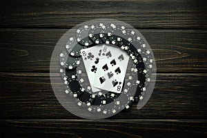 Playing cards in the game of poker with black chips from winning on a vintage table in a clubhouse. Lucky win concept with one