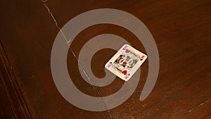 playing cards like poker or rummy, red king of hearts, alone on a dark brown wooden game table