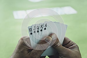 playing cards in a man& x27;s hand on the background of a casino gaming table. Royal flush is best winning combination in