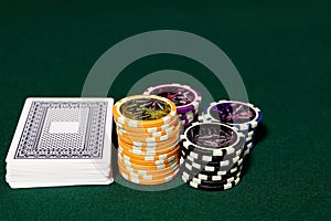 Playing cards and poker chips on agreen table. Stack of chips for poker