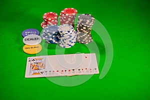 Playing cards, poker chips and dealer button on a green baize