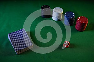 Playing cards, poker chips and a dice on a green table. Game table for leisure.