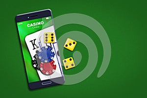 Playing cards, poker chips, and dice, on the smartphone screen. Green background. copy space. Online casino concept