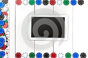 Playing cards, poker chips and tablet on white wooden background. Top view