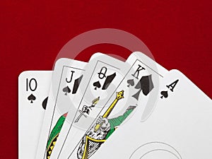 Playing cards. Royal flush on red velvet background