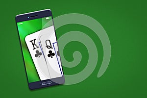 Playing cards on the smartphone screen. Green background. copy space. Online casino concept. Gambling.
