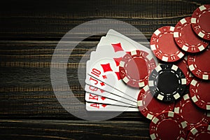 Playing cards with a winning combination of royal flush and chips on a black vintage table in a poker club. Free copy space for