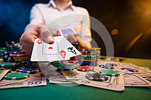 Playing in a casino, online casino. A player opens cards with two aces. Money, poker table, chips. Background for the gaming