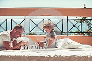 Playing chess with dad - young boy and his father at home.