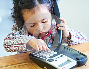 Playing, dial and a child on a telephone phone call for communication in a house. Home, contact and a girl, kid or baby