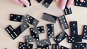 Playing dominoes on a wooden table. Woman's hand with domino. Leisure games concept. Selective focus. Table game girl