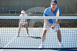 Playing doubles means working together. A mixed doubles team standing ready to receive a serve - Tennis.