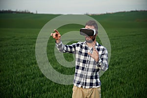 Playing game in VR glasses. Handsome young man is on agricultural field