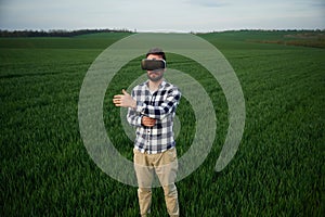 Playing game in VR glasses. Handsome young man is on agricultural field