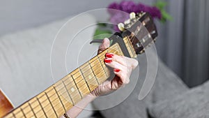 Playing the guitar, changing chords on the fretboard.