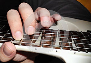 Playing the guitar, hand pressing notes on fretboard of an electric guitar