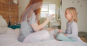 Playing, happy and mother and child with a game, bonding and making a decision on a bed. Smile, family and a young mom