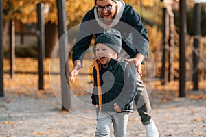 Playing, having fun together. Father and young son is together outdoors at daytime