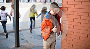 playing hide and seek. boy closed eyes his hands standing at brick wall photo