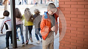 playing hide and seek. boy closed eyes his hands standing at brick wall photo