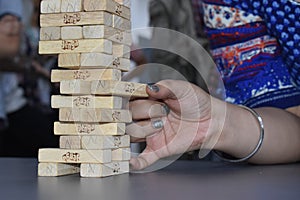 Playing jenga .Close up shot of female Male hand playing wooden blocks tower game .Wood blocks stack game