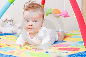 Playing little child on the colored mat for developing