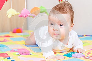 Playing little child on the colored mat for developing