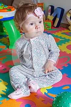 Playing little child on the colored mat for developing, blurred background