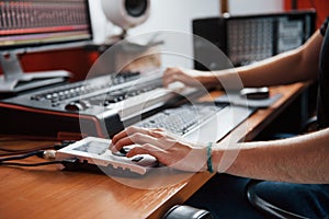 Playing midi keyboard. Sound engineer working and mixing music indoors in the studio