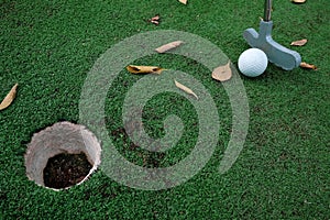 Playing mini golf on artificial green grass outdoors with fallen leaves. Setting goals and winning concept. Fun vacation