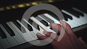 Playing piano only left hand. Media. Close up of person playing musical instrument.