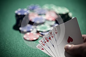 Playing poker in a casino holding winning royal flush hand of cards