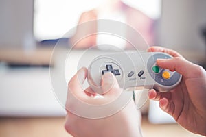 Playing retro video games in living room: Close up of a vintage gaming controller holding in hand